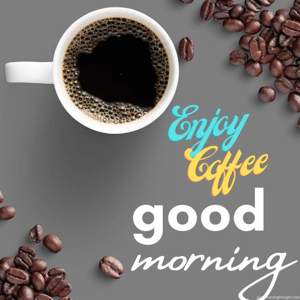 Cup of coffee with coffee beans on gray background with enjoy coffee and good morning written on it