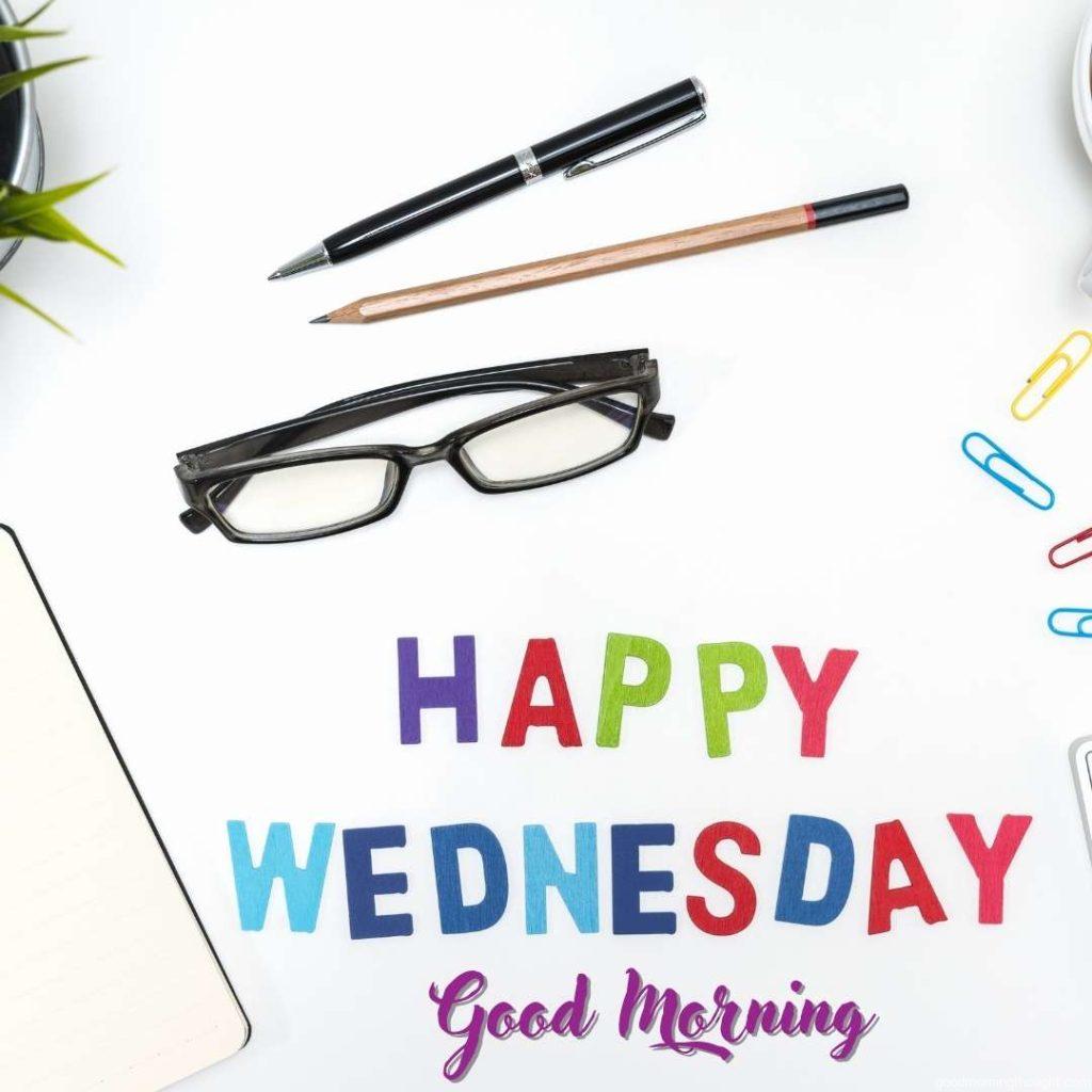 Office desk table with pen, pencil, note book, eye glasses with happy Wednesday message