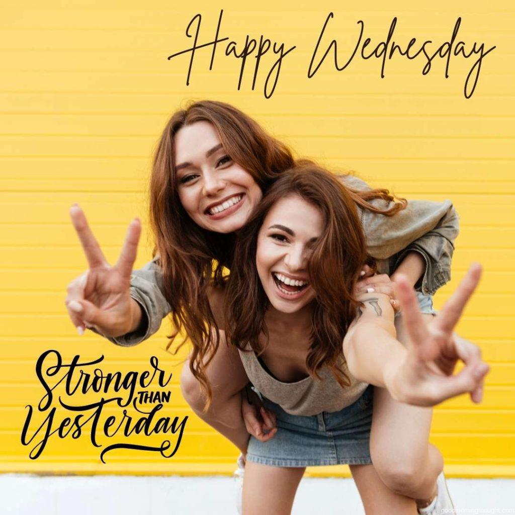 Picture of two young standing women friends standing over yellow wall on Happy Sunday