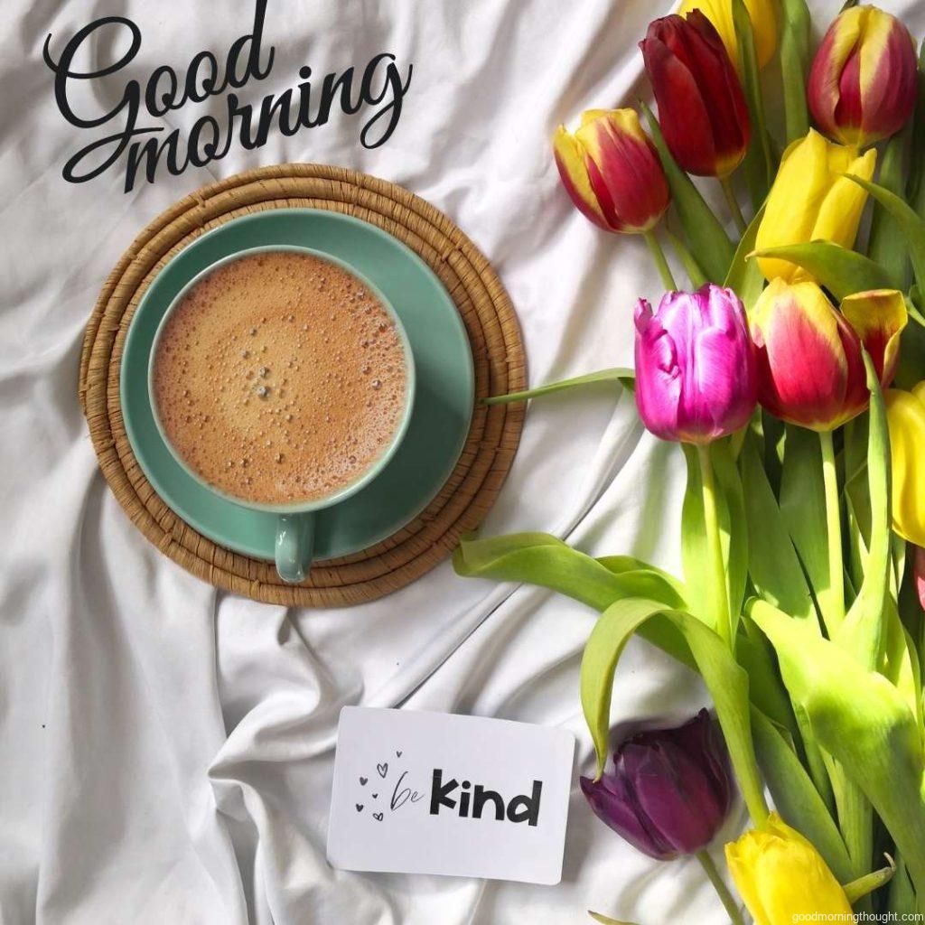 Spring composition with multi colored tulips, coffee cup and quote card sitting on the bed