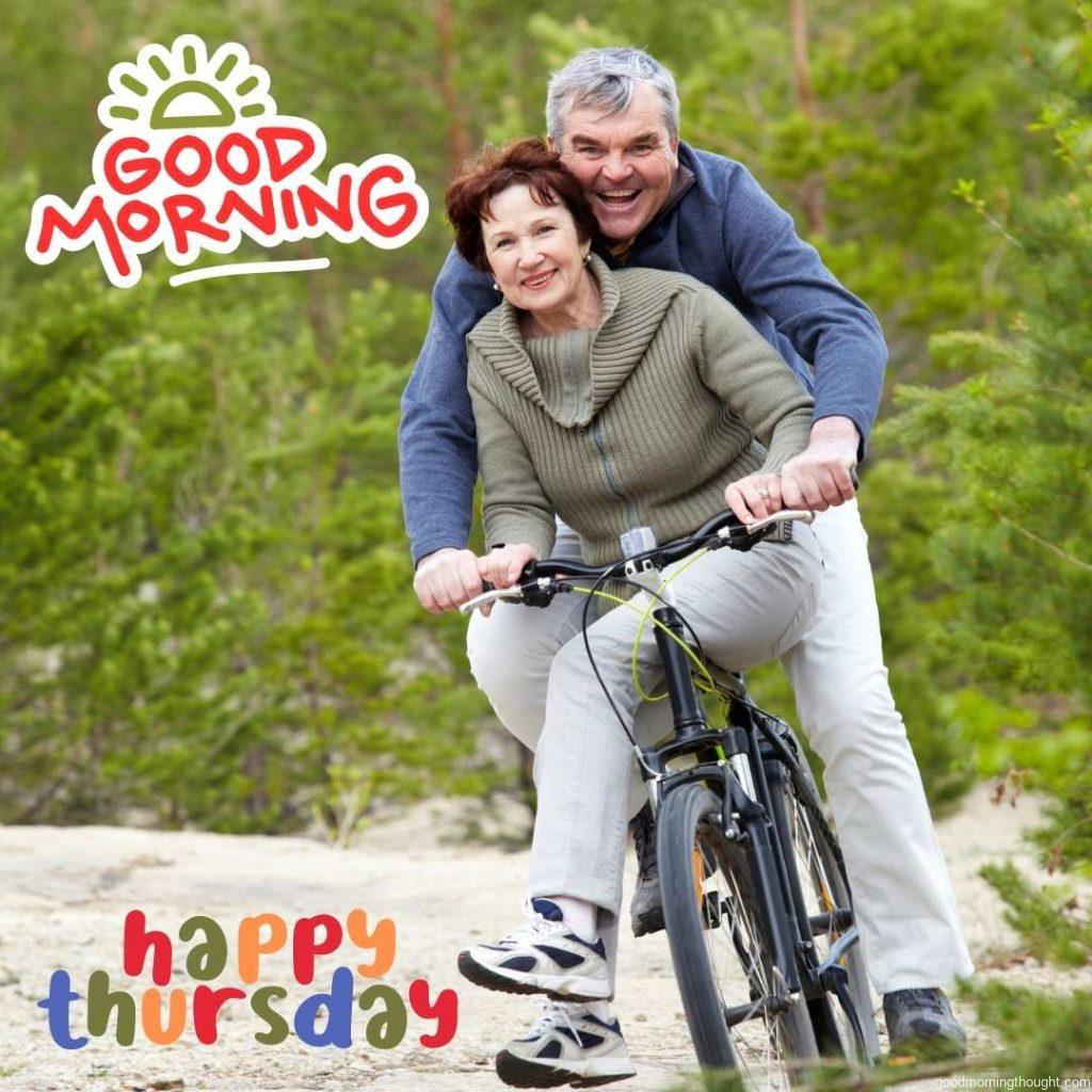 Portrait of a happy mature couple riding bicycles with _Good Morning, Happy Thursday_ text