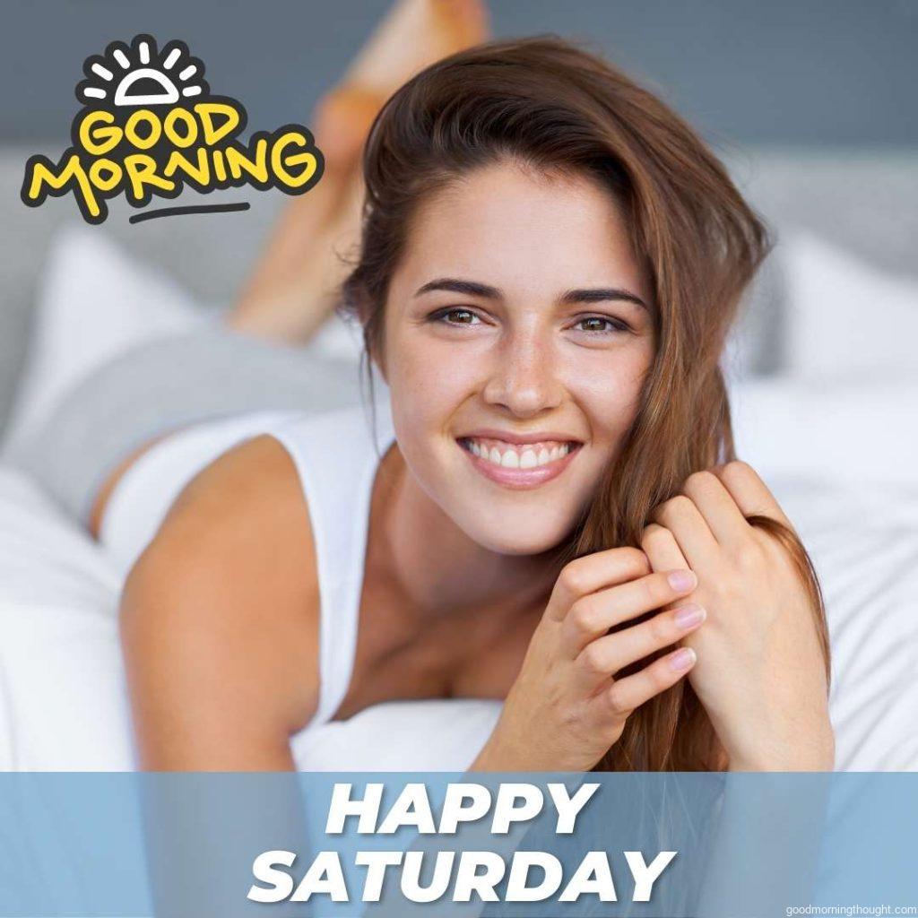 Portrait of a happy young woman lying in bed with the _Good Morning, Happy Saturday_ text