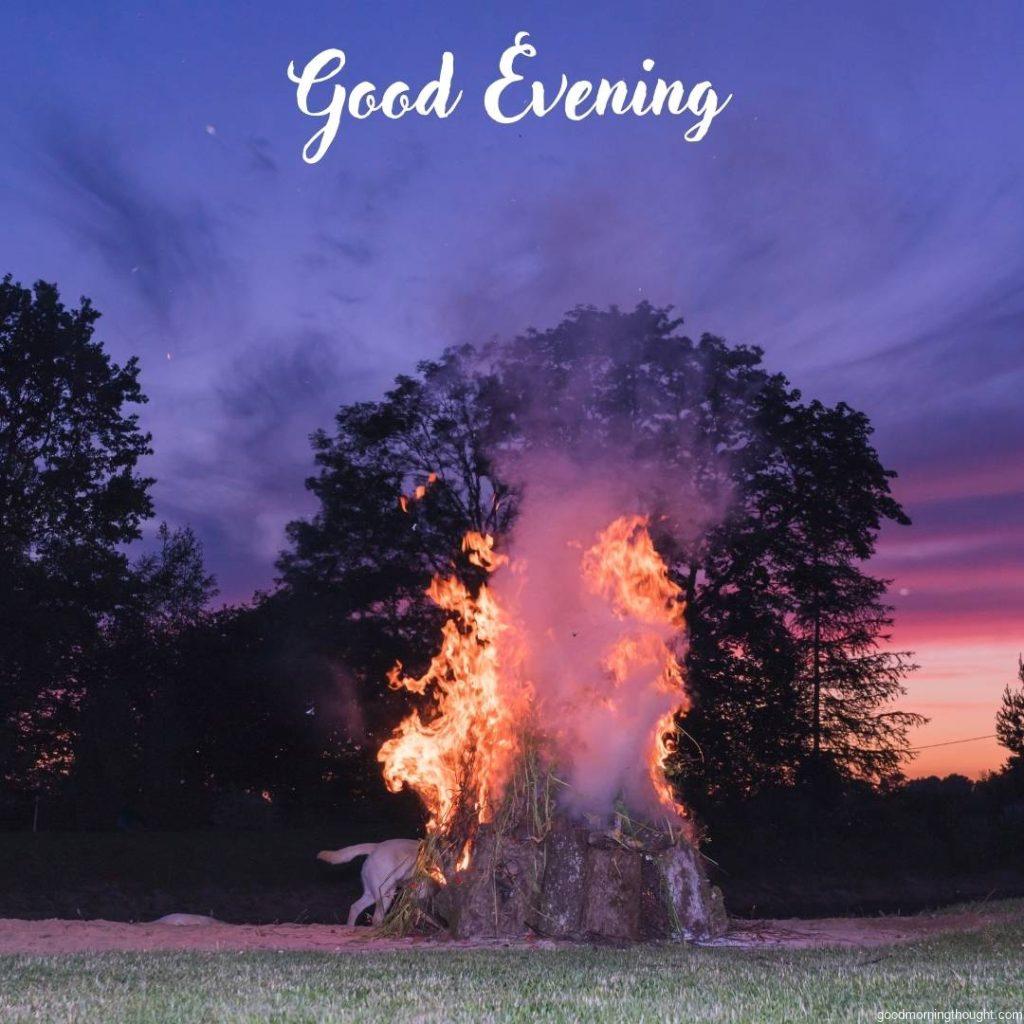 A bonfire on the evening of the summer solstice, with a colorful sunset sky in the background with _Good Evening_ text