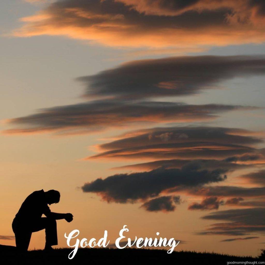 A man prays against a dramatic sky in the evening. Silhouette with _Good Evening_ text