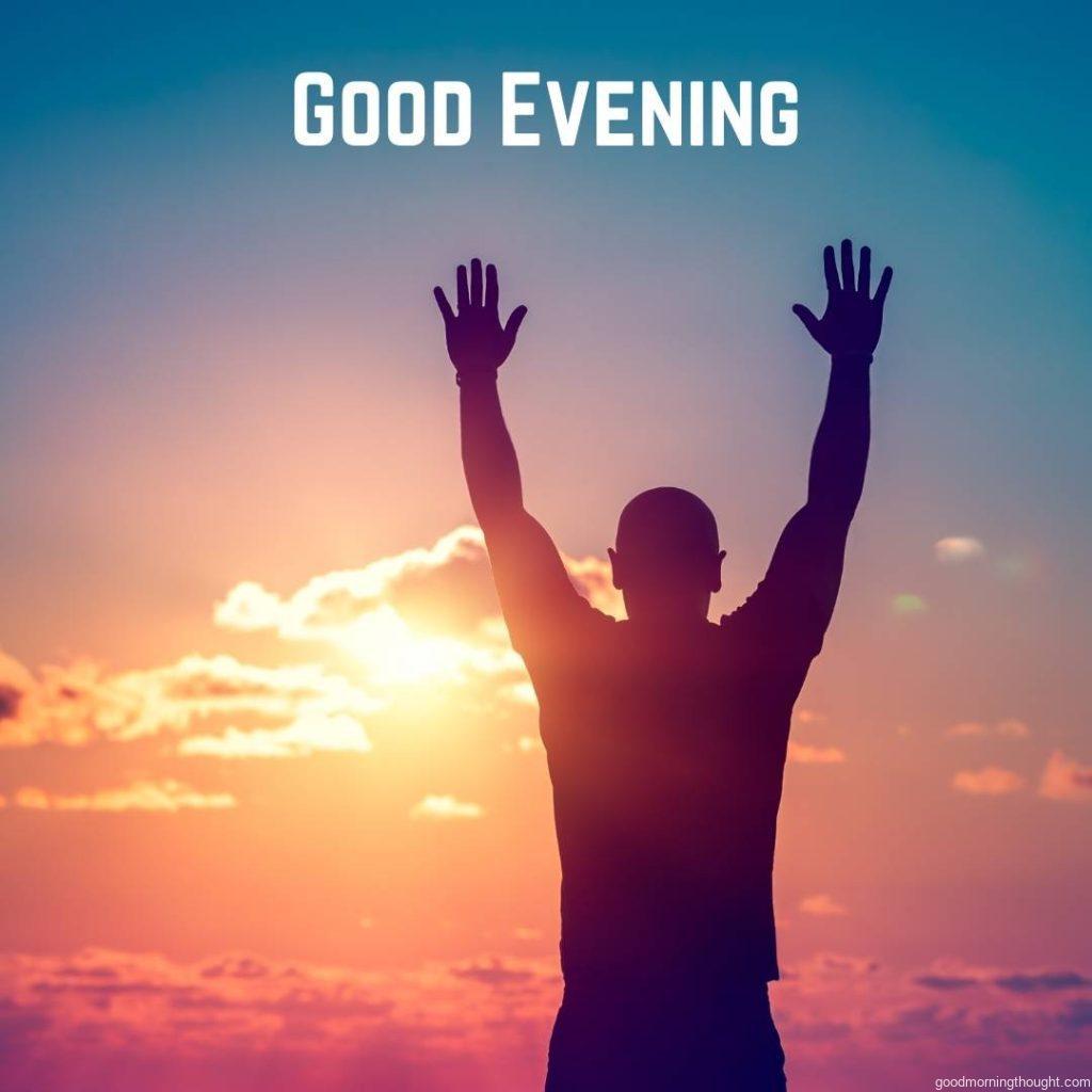 A silhouette of a man with raised hands standing outdoors in the evening, enjoying life and freedom concepts with _Good Evening_ text