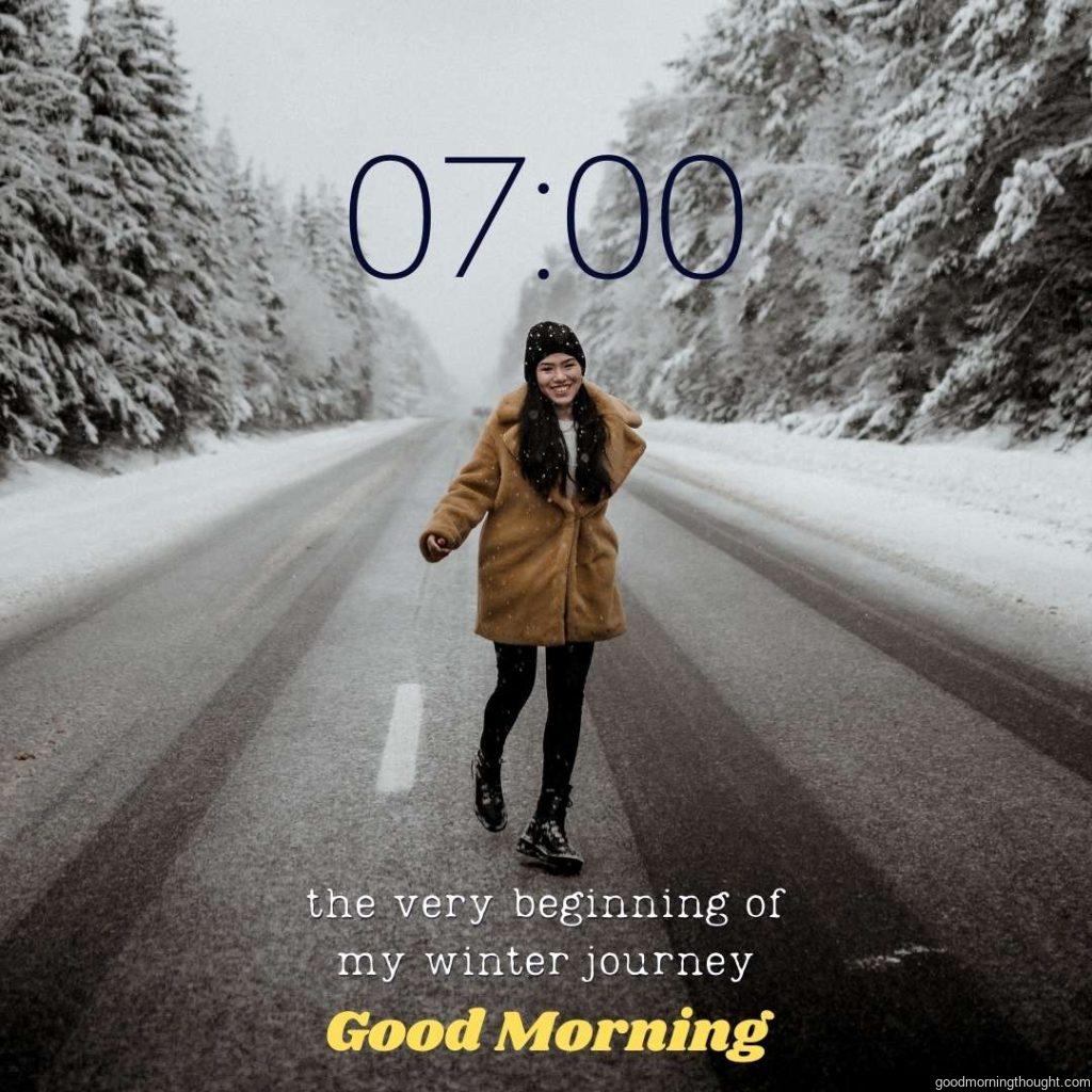 A smiling woman is running on the road in a winter forest. _Good morning_ text