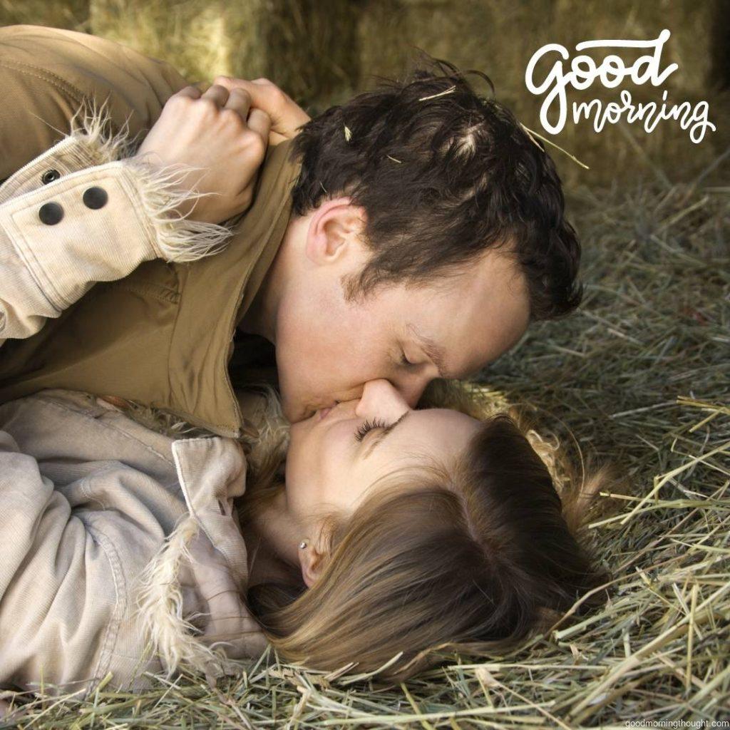 A young adult Caucasian couple lying down in the hay kissing, Love Romantic Kiss Good Morning Image