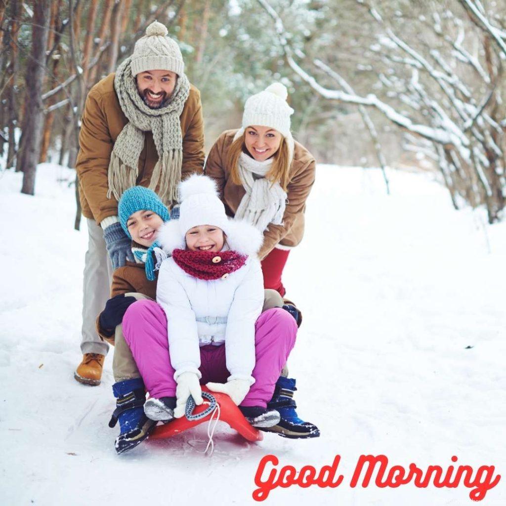 A young family sits on a sled in the snow. _Good morning_ text