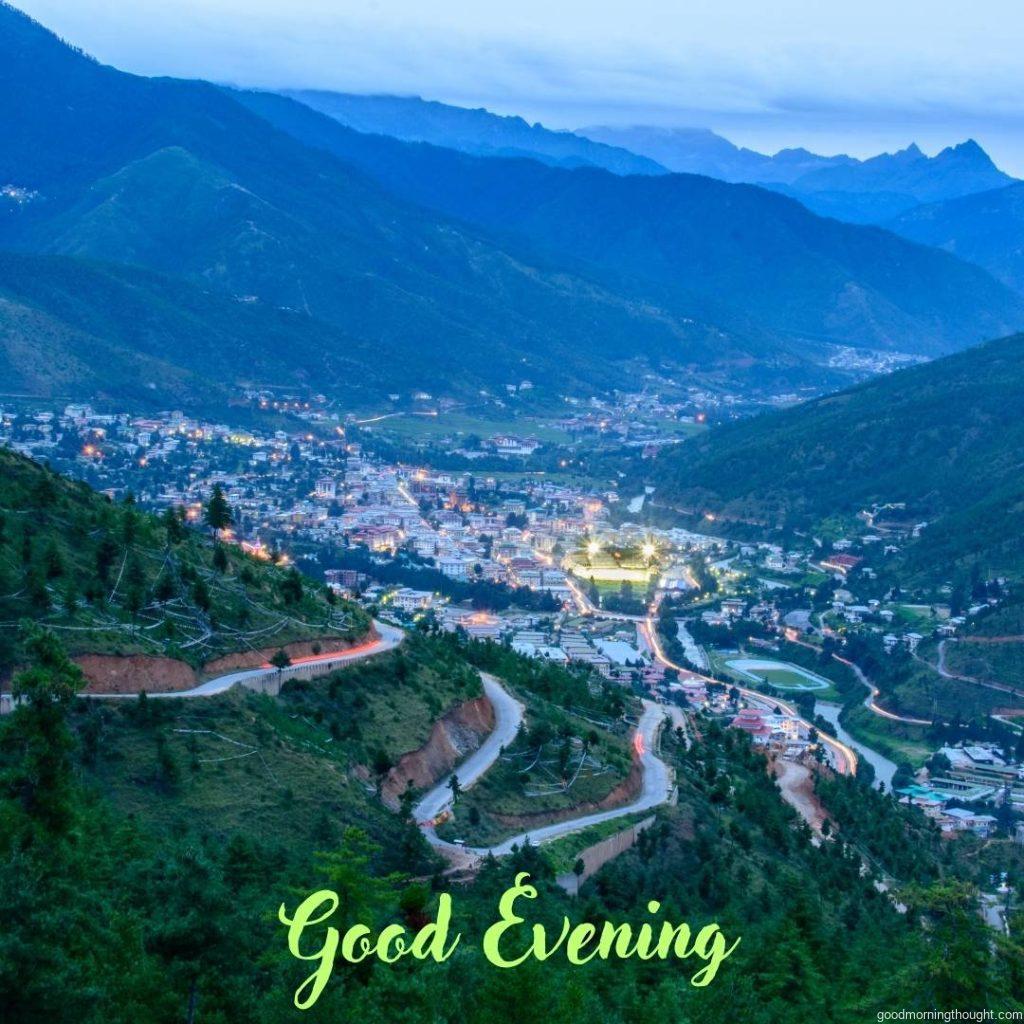 An aerial view of Bhutan’s capital, Thimphu City, surrounded by green hills and forest in the evening, with _good evening_ text