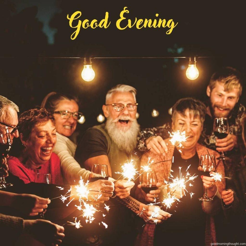 Happy family celebrating with sparklers and fireworks at the party in the evening, _Good Evening_ text