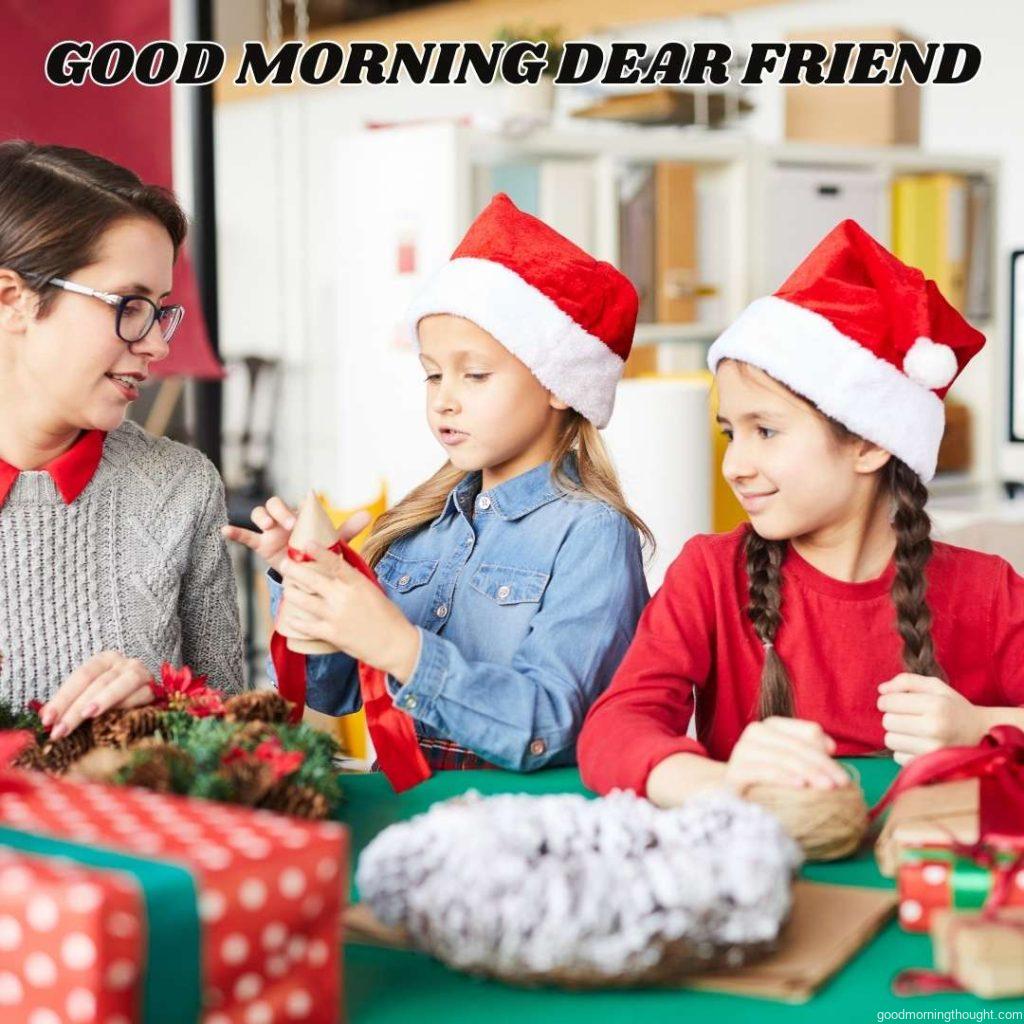 One of the cute girls showed a wooden tree to her mother while tying it up with a red ribbon in the presence of a friend. 