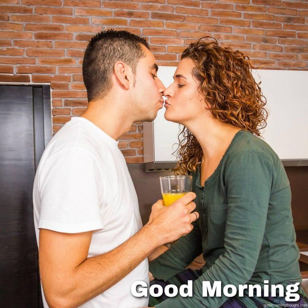 Portrait of a loving young couple kissing while having breakfast in the home kitchen, Love Romantic Kiss Good Morning Image