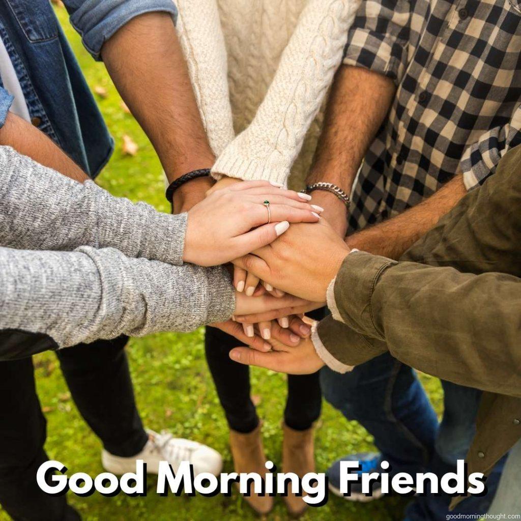 high-angle shot of a group of friends joining their hands together. Good morning text