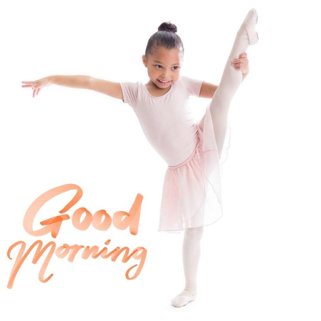 A cute preschool-age African American female ballerina stretches out her leg in ballet pose. Good Morning Text