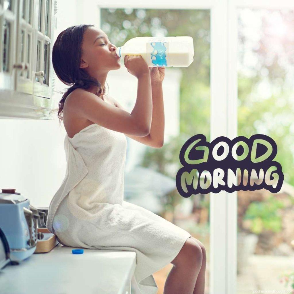 A young woman drinking milk straight from the bottle while sitting on the kitchen counter. African American Good Morning Images