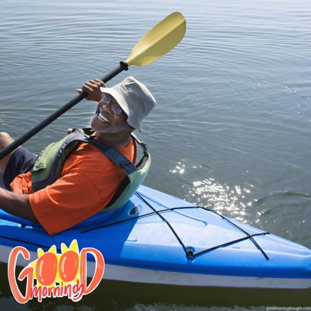 African American middle-aged man smiling at viewer in kayak _Good Morning_ text. Happy Good Morning Images