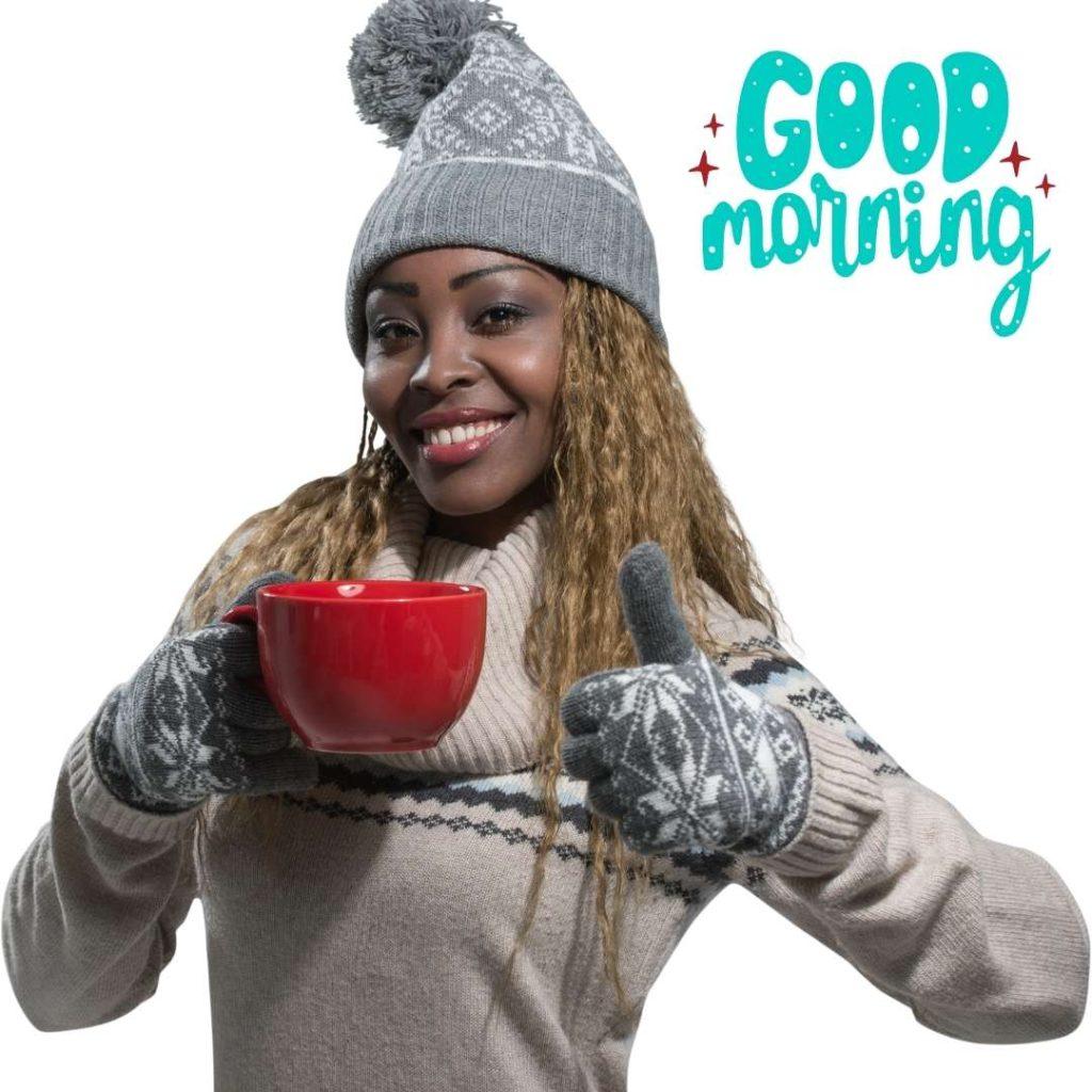 African American woman in winter clothes enjoying a hot drink on a grey background, Good Morning text