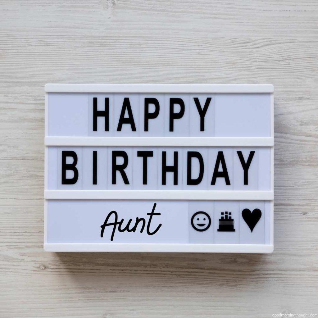 Modern board with the text 'Happy Birthday Aunt' on a white wooden background, top view Flat lay, overhead, from above