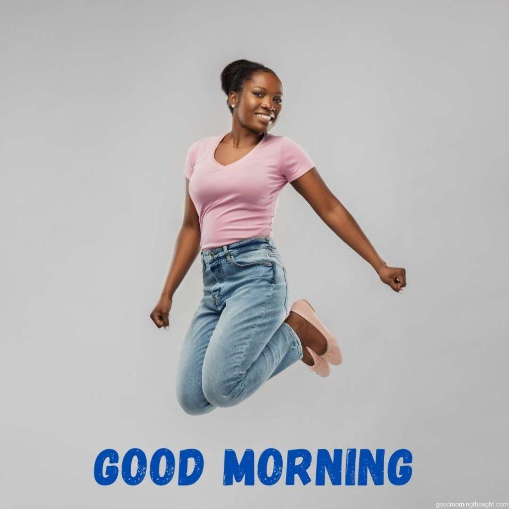 People, ethnicity, and portrait concept_ a happy African American young woman jumping over a grey background, Good Morning Text