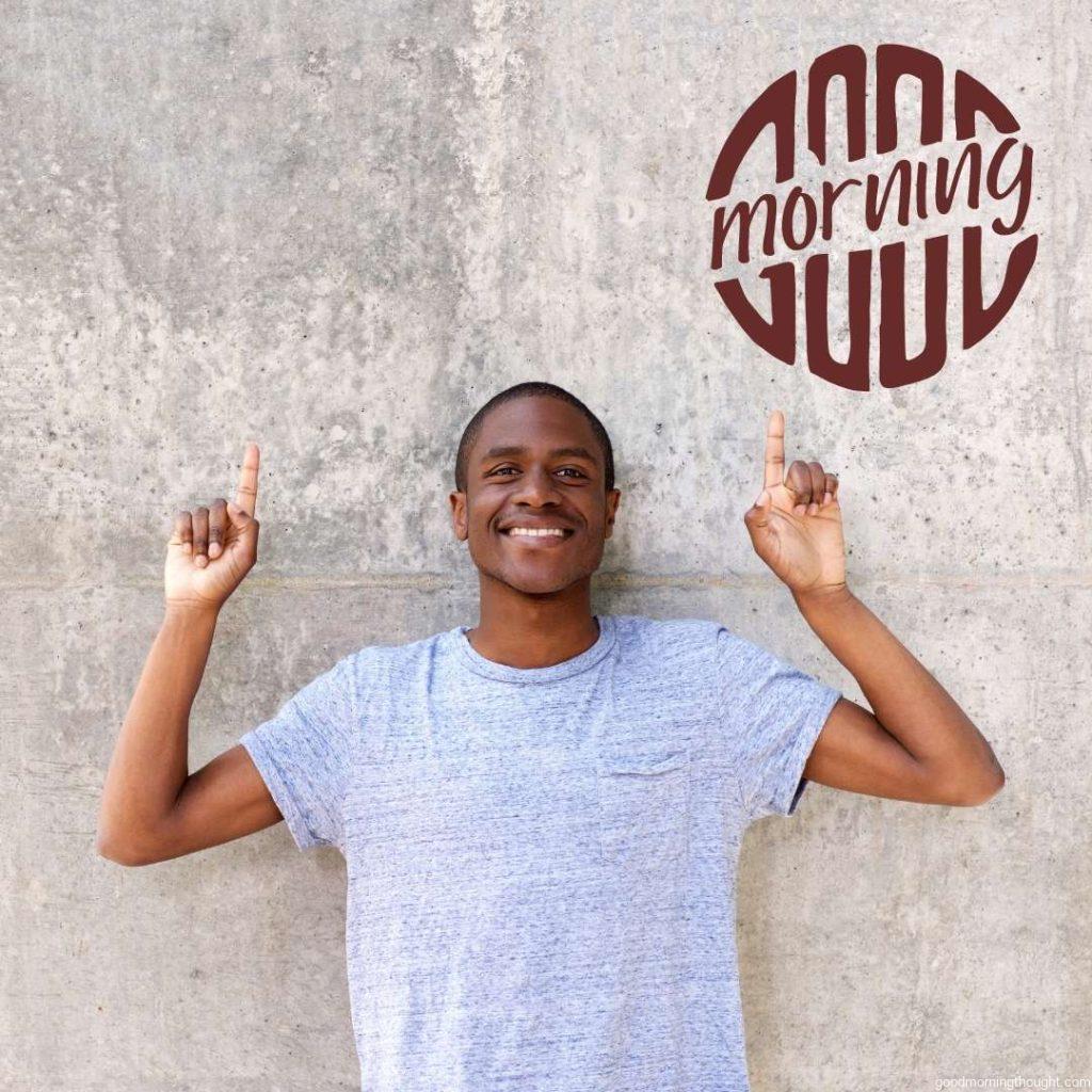 Portrait of a happy African American man smiling and pointing fingers up at copy space, Good Morning Text