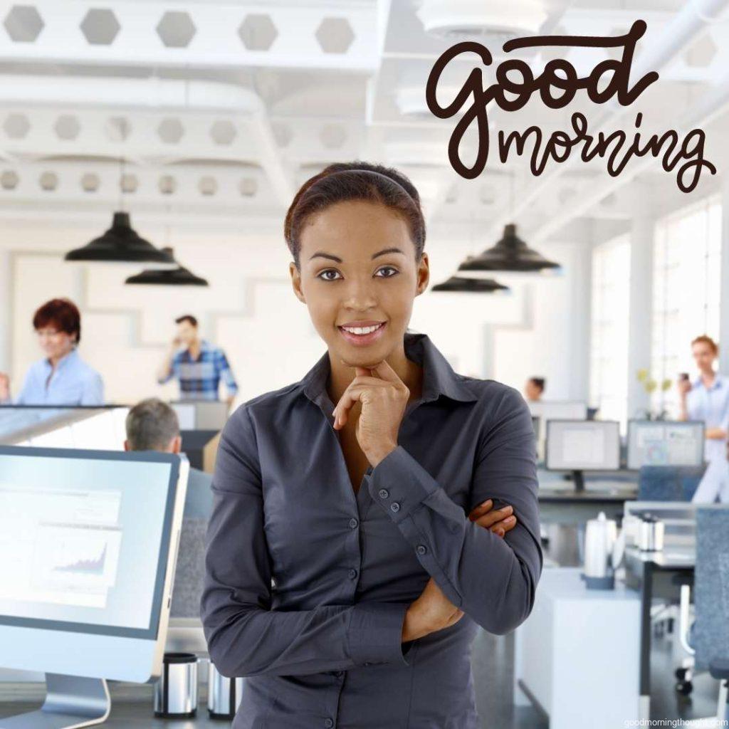 Portrait of a happy black female office worker in the office with working people Good Morning Text