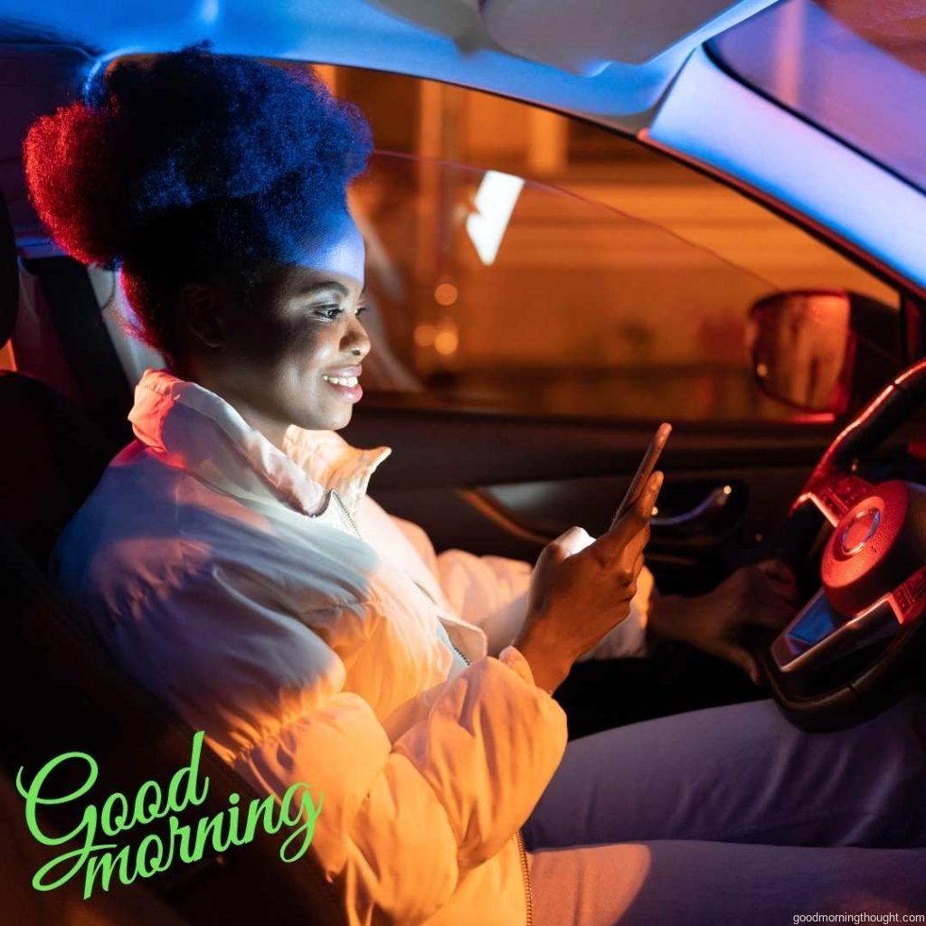 Young women suffer from smartphone addiction; they spend day and night on social media. African girl sits in a dark car holding her mobile phone in hand. Good Morning Text