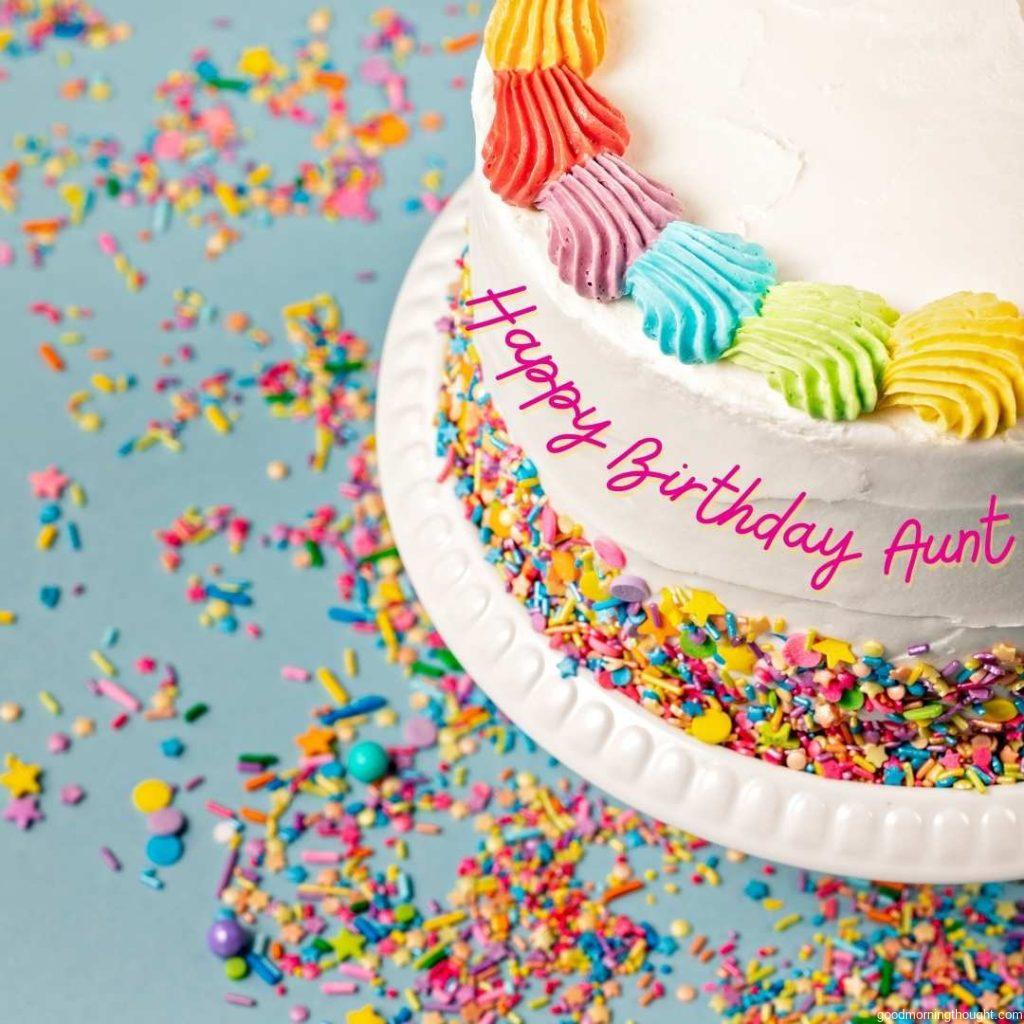 overhead view of a Birthday cake with rainbow icing and colourful Sprinkles over a blue background Happy Birthday Aunt Images